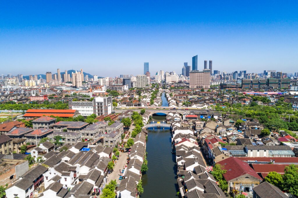 parcours d'acquisition de la citoyenneté: Une vue aérienne d'une ville africaine en pleine expansion avec un quartier historique au bord d'un canal au premier plan et des gratte-ciels modernes à l'horizon ; illustrant l'urbanisation rapide et la croissance des infrastructures sur le continent.