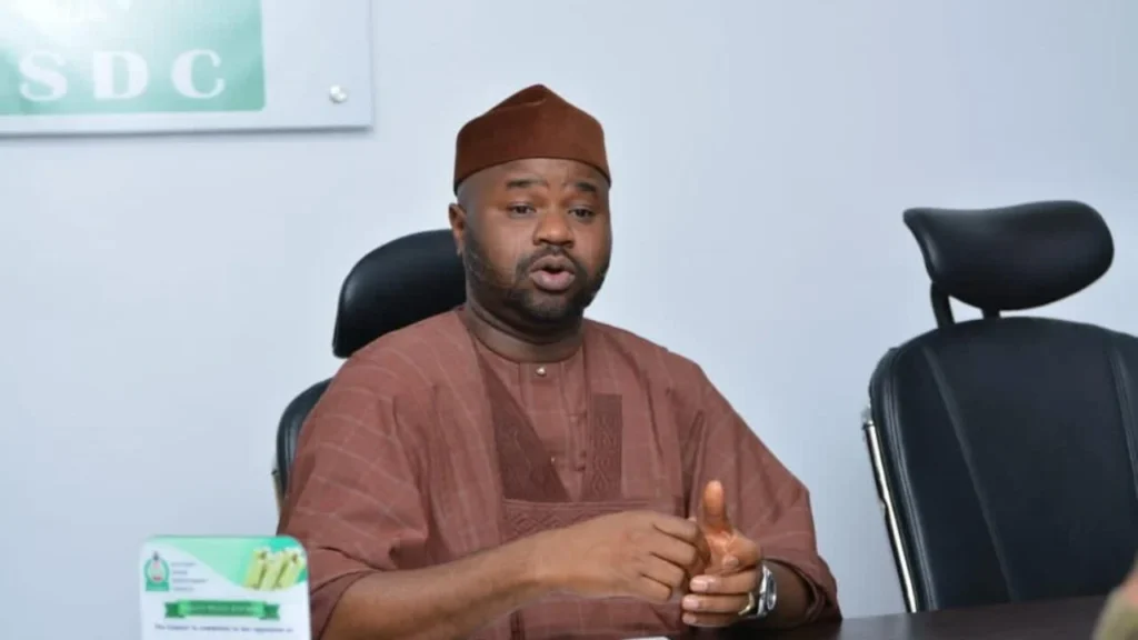 signalement des transactions crypto: Un représentant officiel s'exprimant dans une salle de conférence, symbolisant l'intersection entre le leadership traditionnel et la gouvernance réglementaire moderne dans le secteur financier africain.