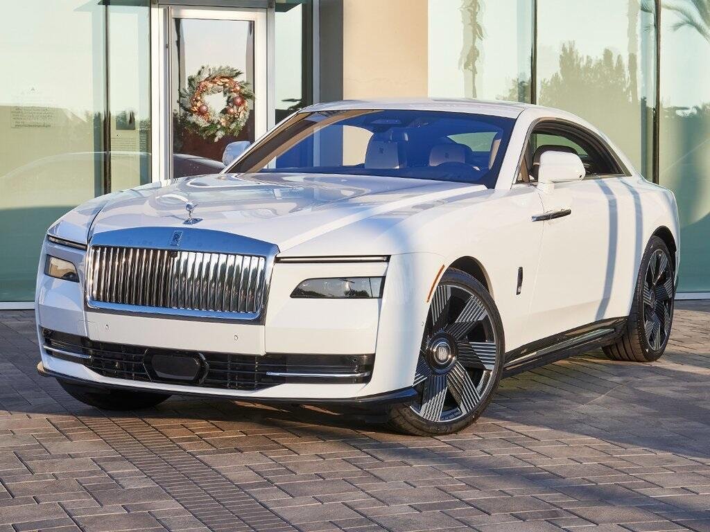 Vue de face d'une Rolls-Royce Spectre blanche sur une allée pavée ensoleillée, représentant le lifestyle haut de gamme contemporain en Afrique.