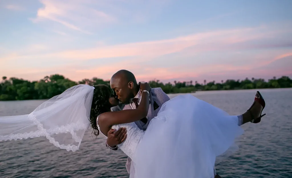 La révolution intime : Pourquoi les Elopement Destinations 2026 redéfinissent le romantisme: Un couple africain célébrant son mariage au crépuscule au bord de l'eau, mettant en avant la mode nuptiale d'élite et l'événementiel haut de gamme.