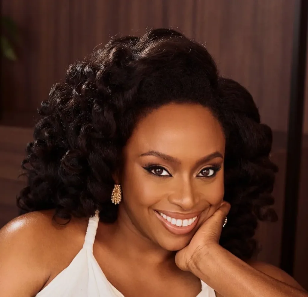 surmonter la stagnation créative: Chimamanda Ngozi Adichie, voix majeure du féminisme mondial et du récit africain contemporain, posant dans une robe dos nu blanche ; symbolisant la force et l'élégance du leadership intellectuel africain.