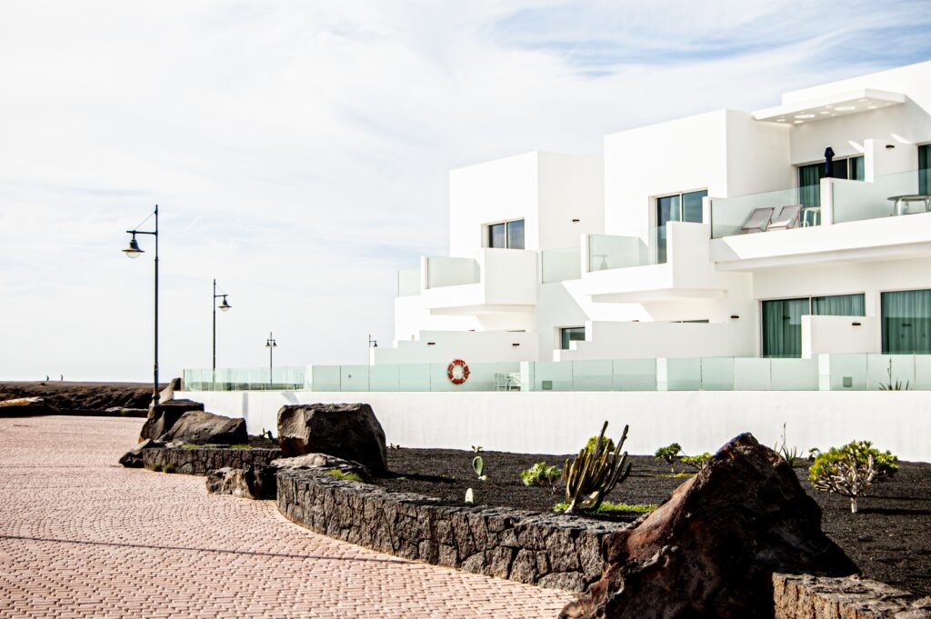 Une rangée de villas résidentielles blanches modernes et minimalistes avec des balcons en verre sous un ciel dégagé ; représentant la croissance de l'immobilier de luxe et de l'investissement locatif premium.